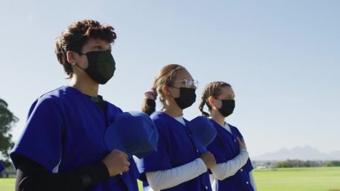 戴着口罩的女棒球运动员组成的多元化团队站在心脏上