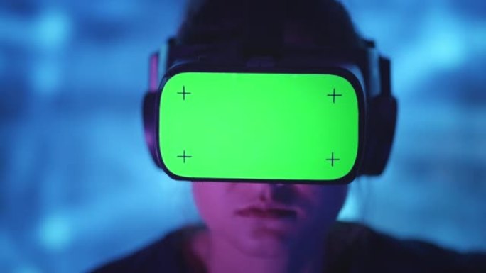 女人在家里的VR耳机上有色度键绿色屏幕，背景为霓虹灯。