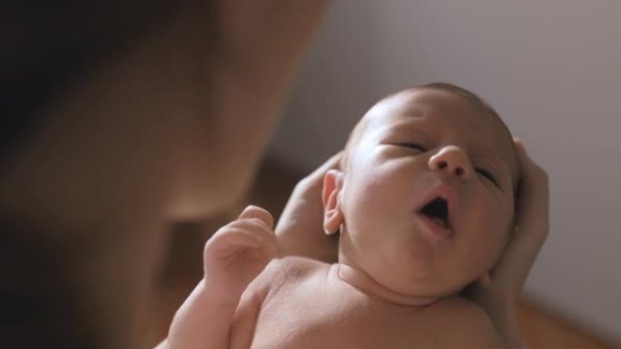 一个新生婴儿在母亲怀里哭泣的慢动作特写。父母安抚她的小宝宝入睡的真实照片。母性、新生活和分娩的概念