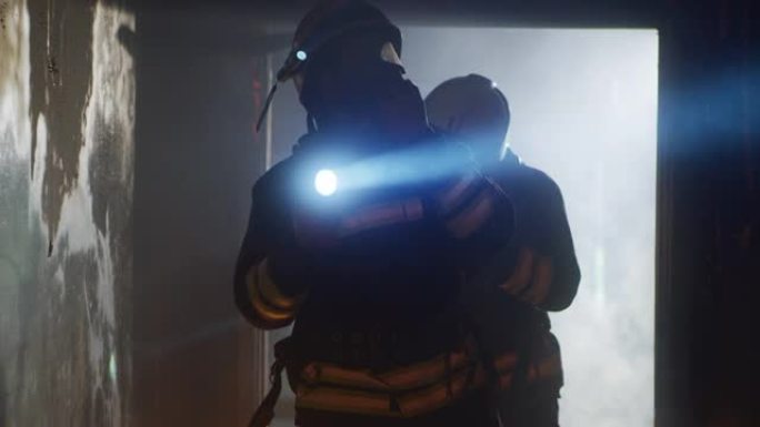 消防员带着手电筒走过烧毁的走廊