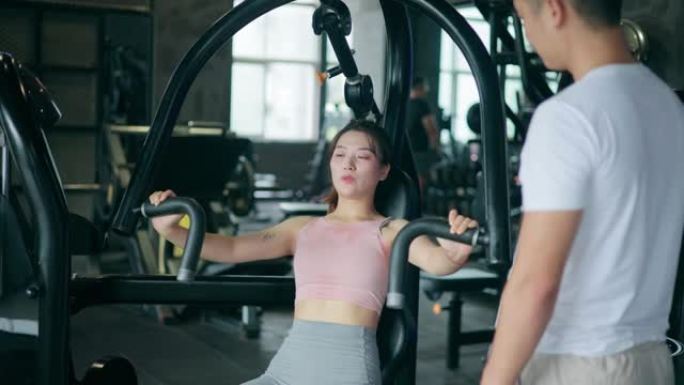 在健身房做胸部锻炼的年轻女性