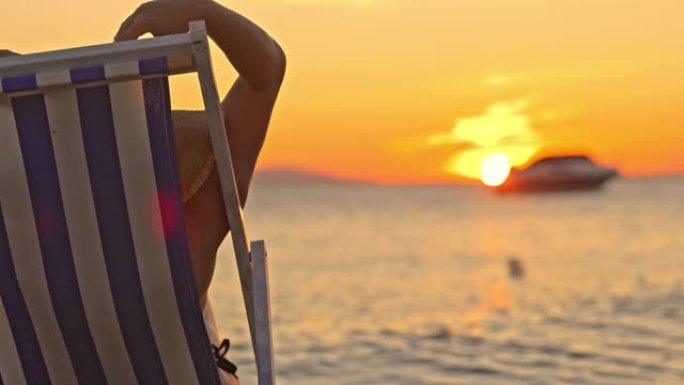 SLO MO无法识别的女人在海滩上欣赏日落时举起双臂向天空