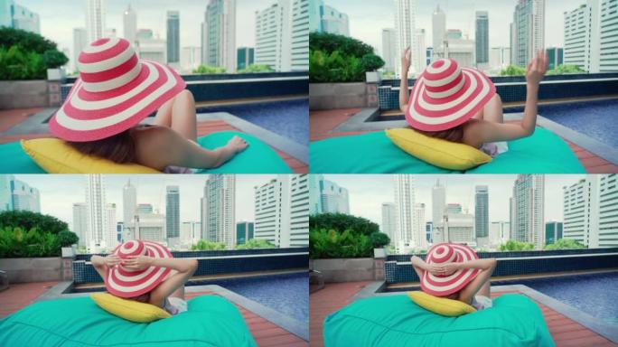 亚洲女商人在游泳池休息时携手触摸度假帽子
