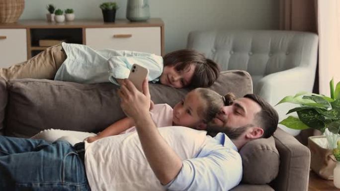 父亲和孩子躺在沙发上看电话卡通