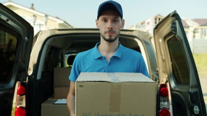 穿着制服拿着纸箱的送货员的肖像站在面包车附近，带着包裹