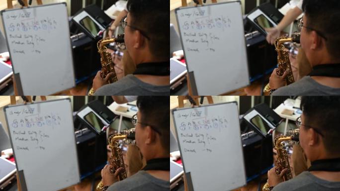 亚洲中国中年男子从音乐工作室的教练那里学习乐器演奏萨克斯管