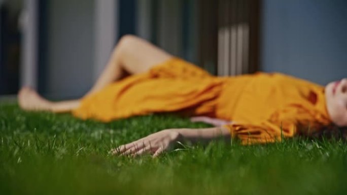 SLO MO年轻女子躺在草坪上时碰到绿草