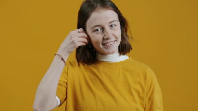 现代女孩的肖像使用耳罩和点头在黄色背景上跳舞