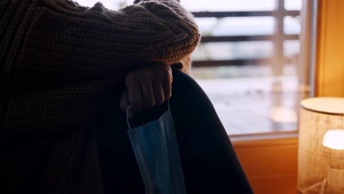 SLO MO沮丧的女人在新型冠状病毒肺炎锁定期间透过窗户看时拿着手术面罩