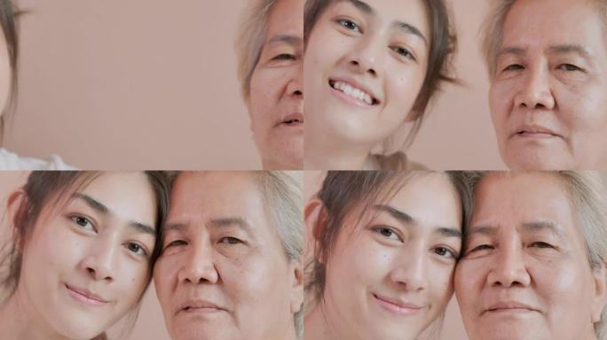 特写，肖像快乐志愿者亚洲年轻女性看守人与亚洲老年母亲病人在家里看相机。家庭工作室