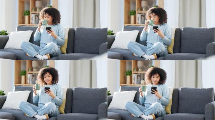 女人在家里喝咖啡时在手机上阅读短信，在线浏览社交媒体或浏览应用程序。一位快乐，微笑和舒适的黑人女性喝