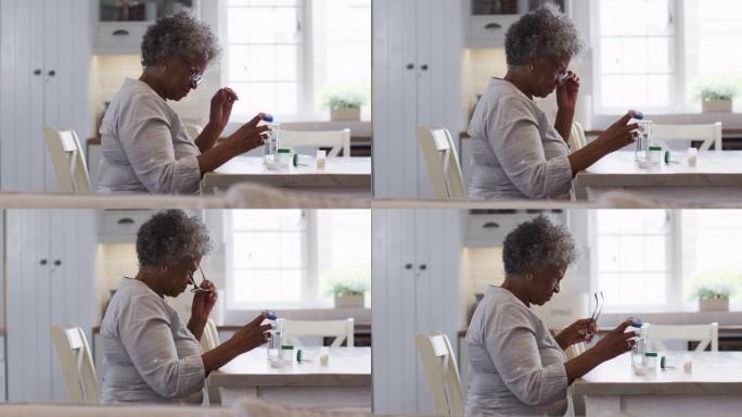 资深非裔美国妇女坐在家里看着空的药物容器