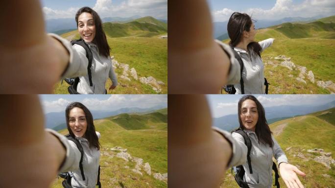 一位背着背包的无忧无虑的女游客正在向朋友或亲戚进行自拍或技术视频通话，而在绿色自然环绕的山丘中徒步旅