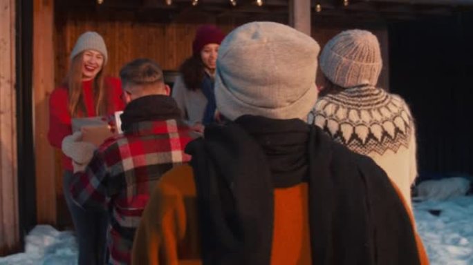 快乐的年轻男女从车顶拿圣诞礼物，在冬季派对慢动作中会见和拥抱朋友。