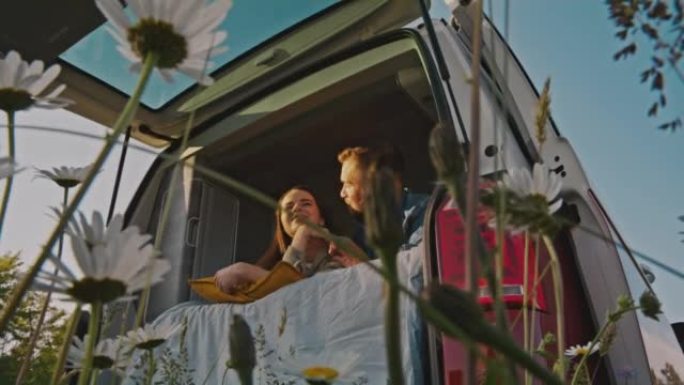 洛杉矶年轻的情侣躺在草地上的露营车里玩得开心