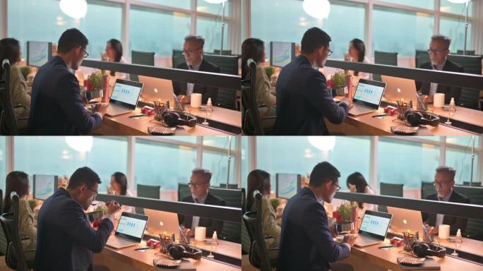 亚洲华裔年轻商人在办公室工作，并在工作场所用餐nasi lemak使用笔记本电脑处理报告