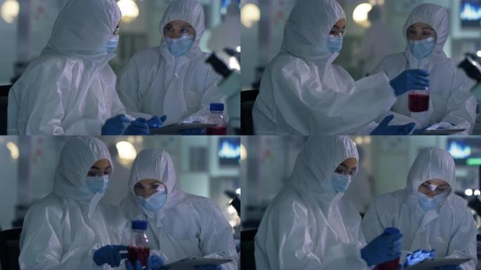 两名科学家在实验室的数字平板电脑上一起工作时穿着辐射服的4k视频片段