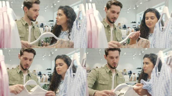 在现代商店中，快乐的夫妇选择衣服讨论衣服在衣架上触摸衬衫