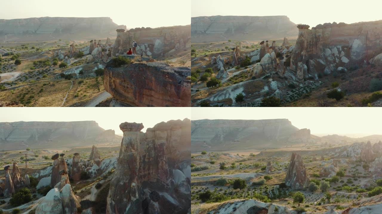 旅行和旅行。空中背景拍摄，快乐的年轻旅游男女享受史诗般的日出沙漠风景。