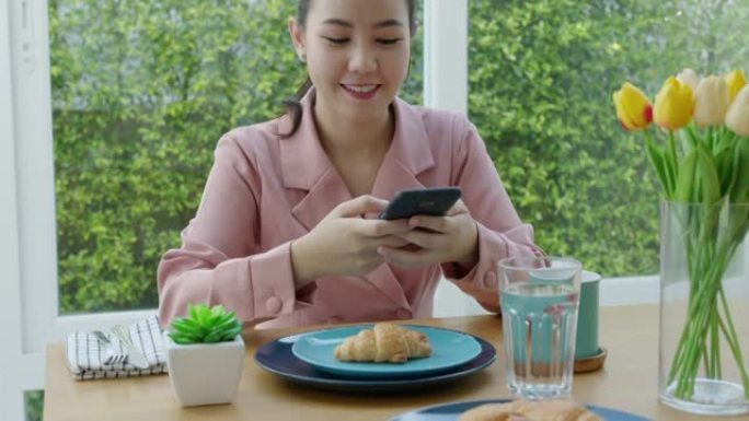 亚洲女人拍照片美食评论社交媒体通过手机咖啡馆。