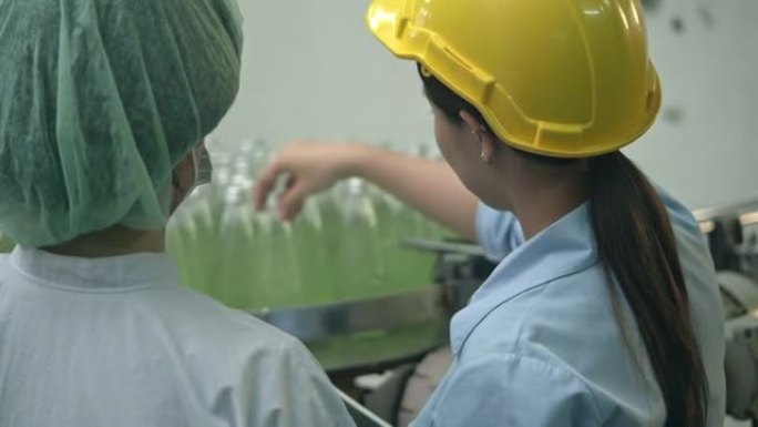 两名工厂工人在传送带上连续检查瓶子