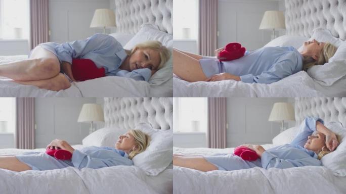 更年期成熟的女人躺在家里的床上拿着热水瓶-慢动作拍摄