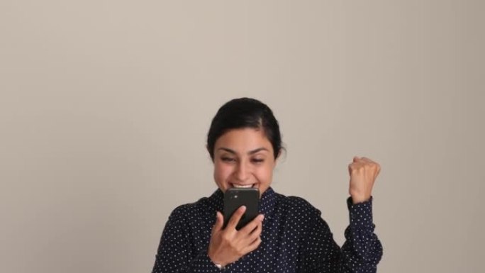 女人使用智能手机阅读短信庆祝好消息，工作室拍摄