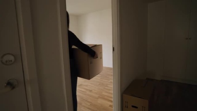女人把一个盒子搬进她的新公寓