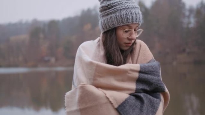 年轻女子站在湖边时用披肩包裹自己