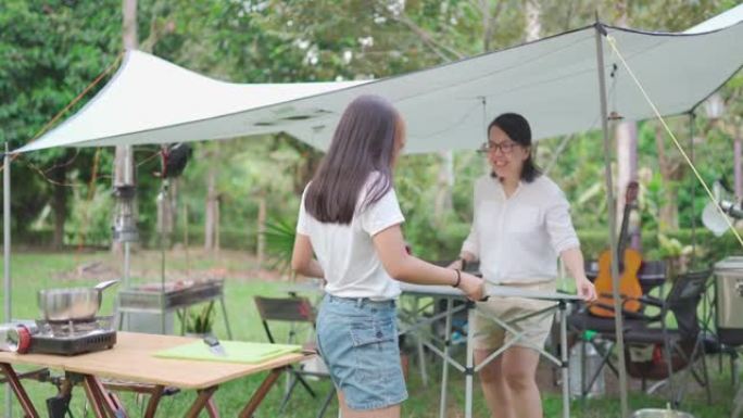 亚洲华人母女在露营地摆放野餐桌准备食物