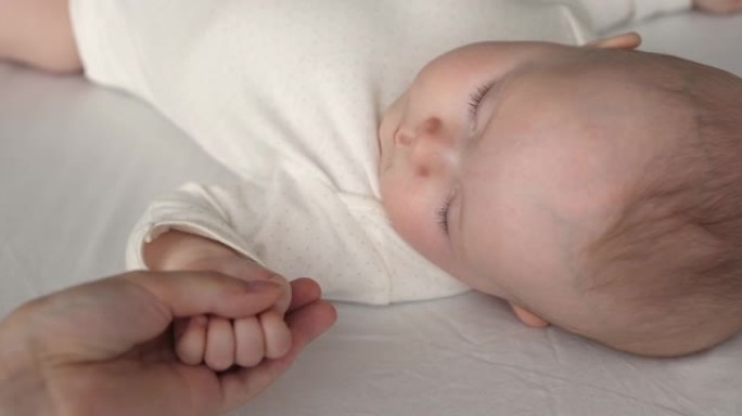 慈爱的母亲在孩子睡觉时抚摸婴儿的小臂