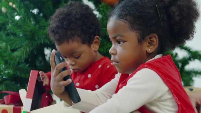 圣诞节那天，两个孩子的快乐家庭非洲民族在视频会议上通过智能手机在家进行视频通话。亲密的圣诞节概念。