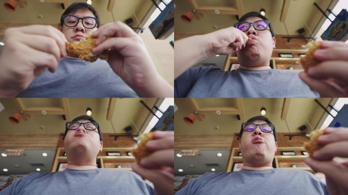 低角度视角男子在慢动作中吃炸鸡