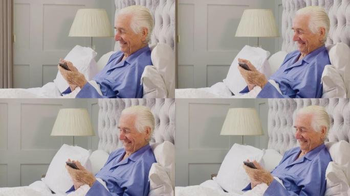 微笑的老人在家穿着睡衣躺在床上用手机
