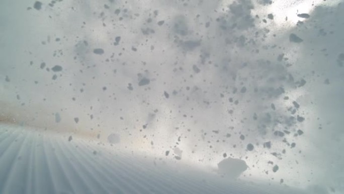 低角度: 凉爽的年轻男性滑雪者向相机喷洒修饰的粉末雪。