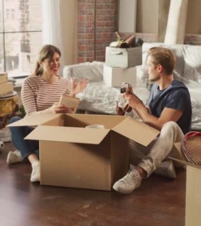 垂直屏幕: 快乐的房主搬进来: 可爱的夫妇坐在舒适公寓的地板上打开纸板箱。抵押贷款，房地产，年轻家庭