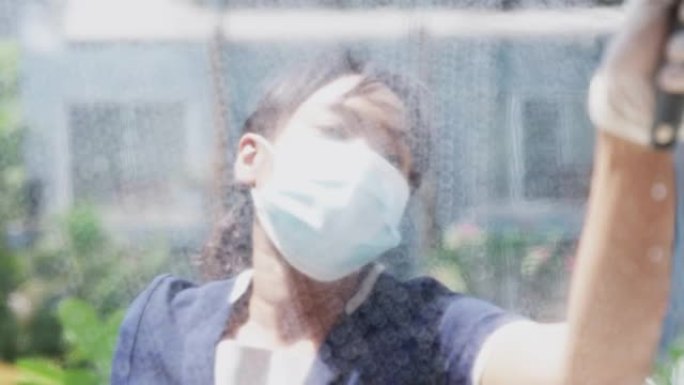 一个疲惫的管家在阳光下清理玻璃时的特写镜头。她疲倦地工作。