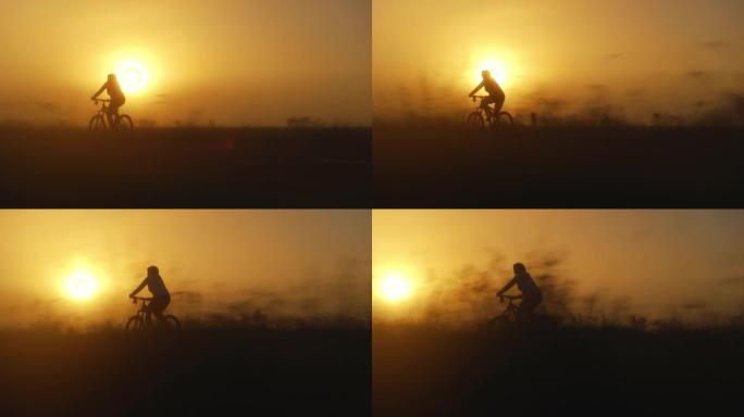 日落时骑自行车的女人的剪影