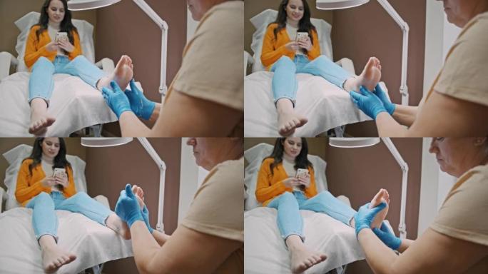 SLO MO足疗师在使用手机时按摩年轻女子的脚