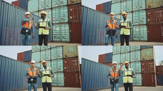 英俊的工业工程师和非裔美国人主管，戴着安全帽的平板电脑和安全背心走在集装箱码头上。同事们谈物流运营。
