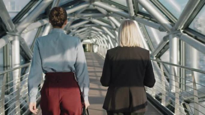 成功的商业女性沿着玻璃桥行走