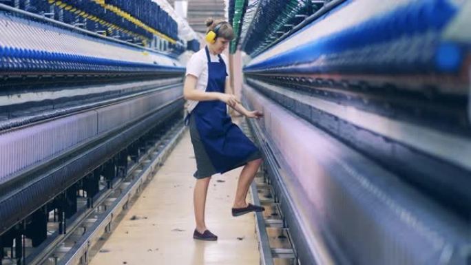 一名妇女在纺织厂单位与线轴一起工作