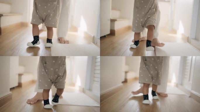 小孩和母亲的腿的特写镜头，而他们正在练习走路。