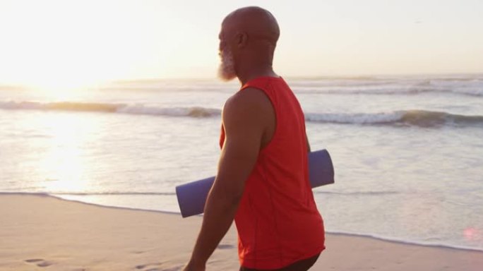 资深非裔美国男子在沙滩上与瑜伽垫同行