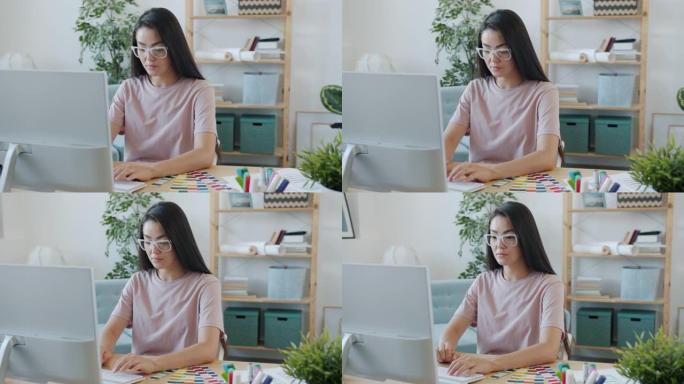 严肃的亚洲女孩创意设计师的肖像与电脑打字看调色板