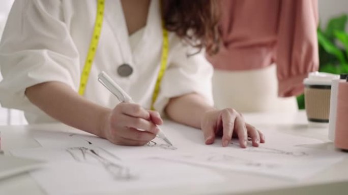 特写女设计师在现代工作室用笔记本电脑画衣服素描