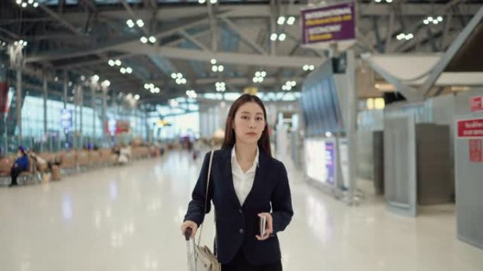 穿着制服的女雇主拉着行李箱在机场航站楼散步