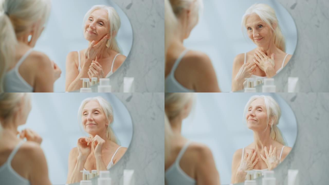 美丽的高级女人早上浴室例行公事，看着镜子用手的感官动作触摸她的脖子。老年女性自然美。晚年的尊严和优雅