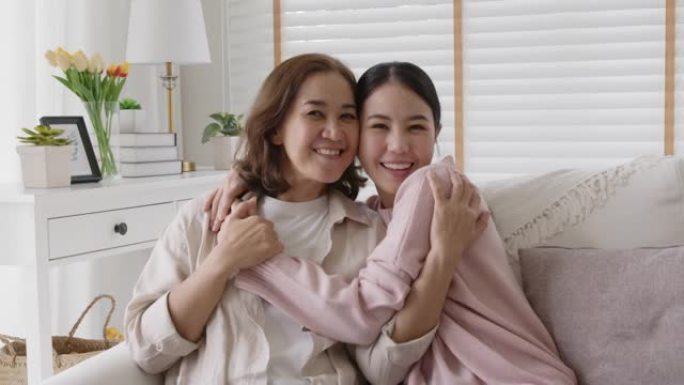 亚洲家庭母女在家里沙发上拥抱拥抱。