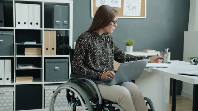 截瘫的上班族坐在轮椅上，使用笔记本电脑打字专注于商务活动